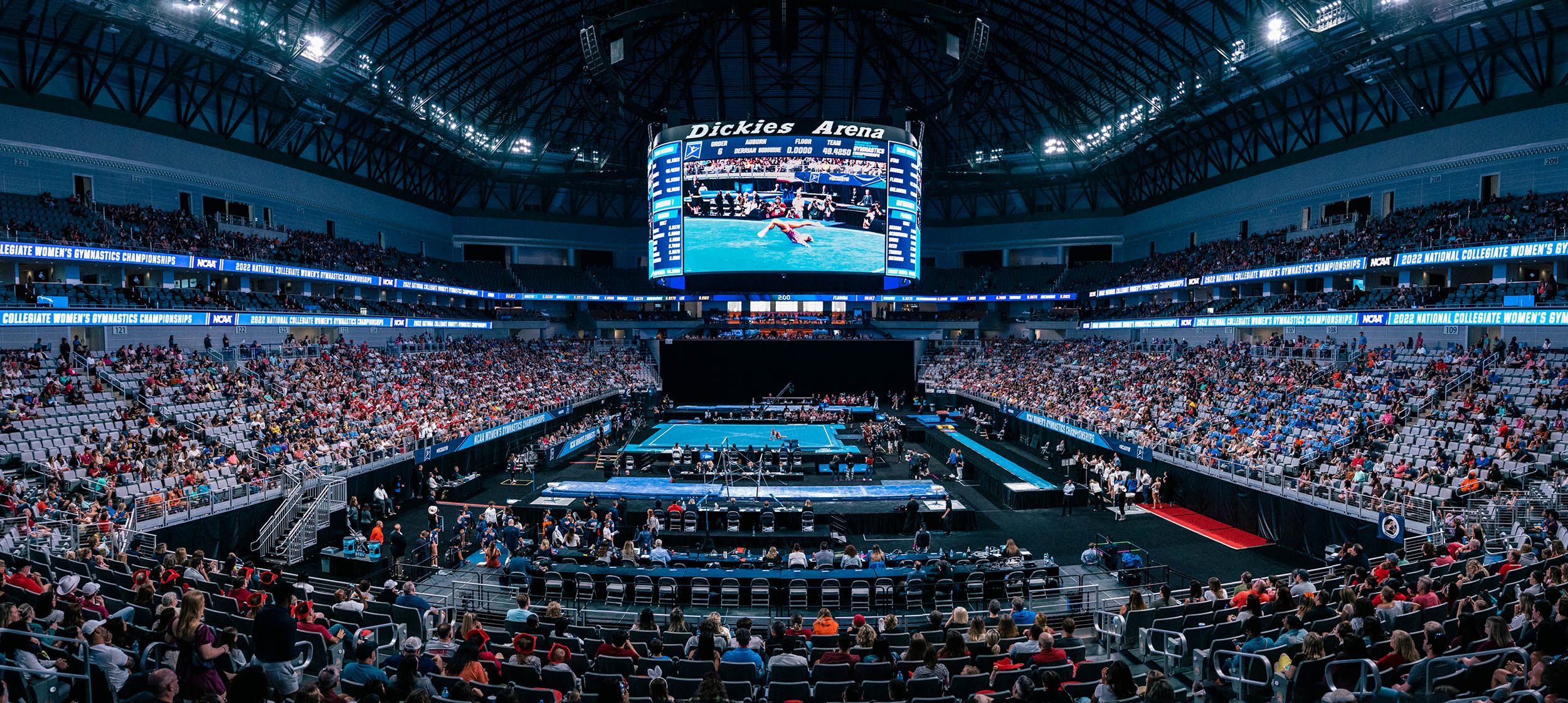 View from the stands at a college gymnastics competition in a large stadium.