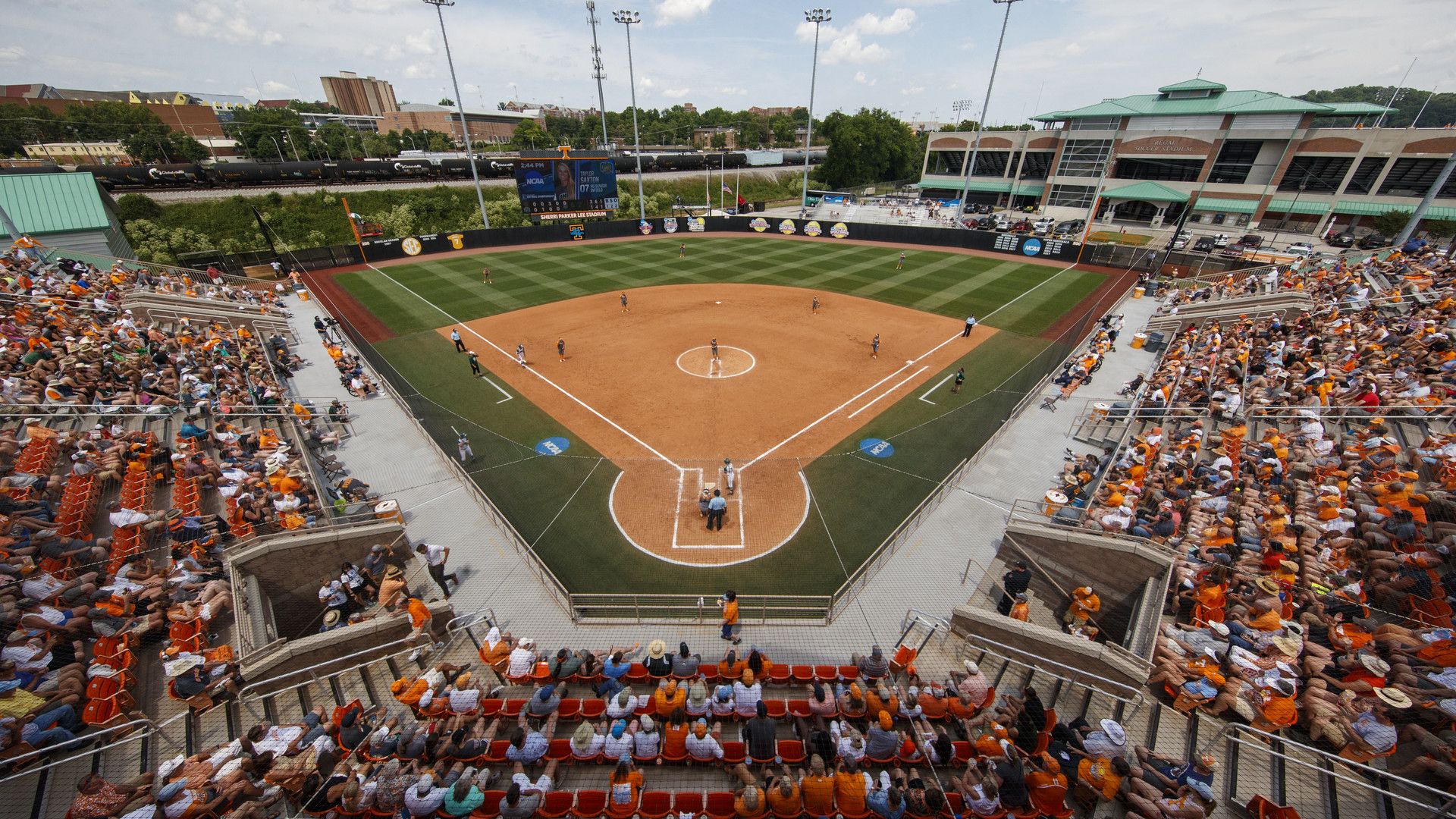 Aerial view of a packed stadium at a college softball game.