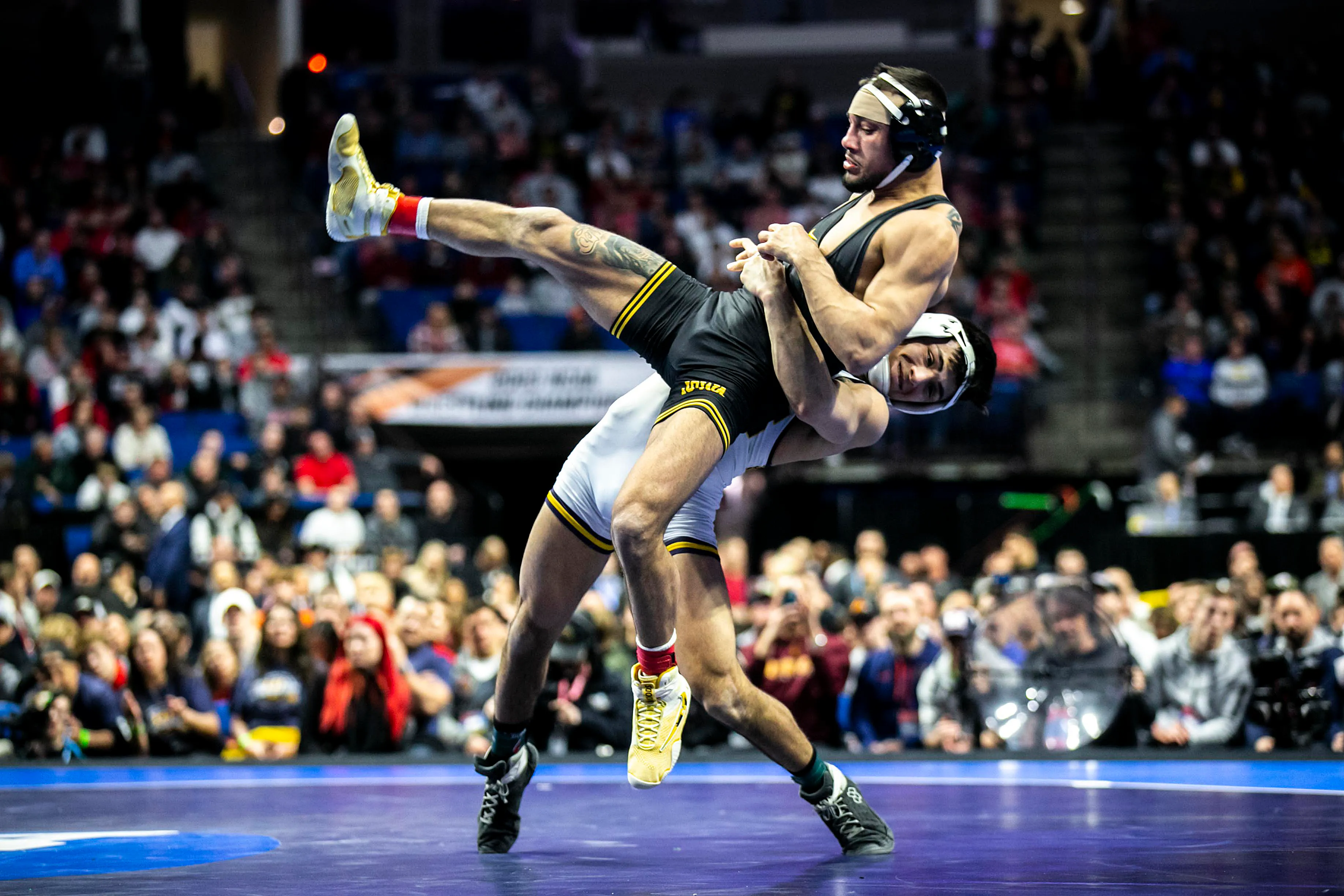 Two college wrestlers in an intense duel on the mat.