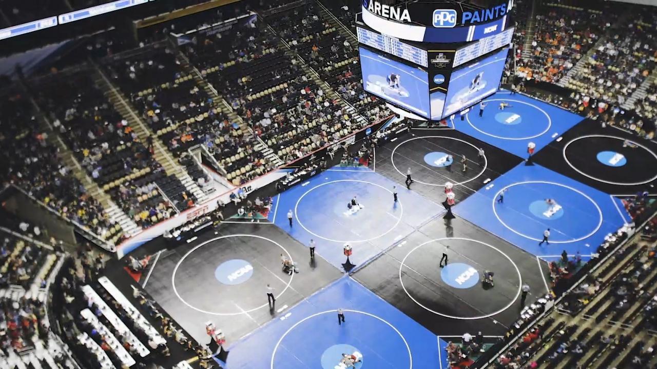 Aerial view of an NCAA wrestling match in a packed stadium.